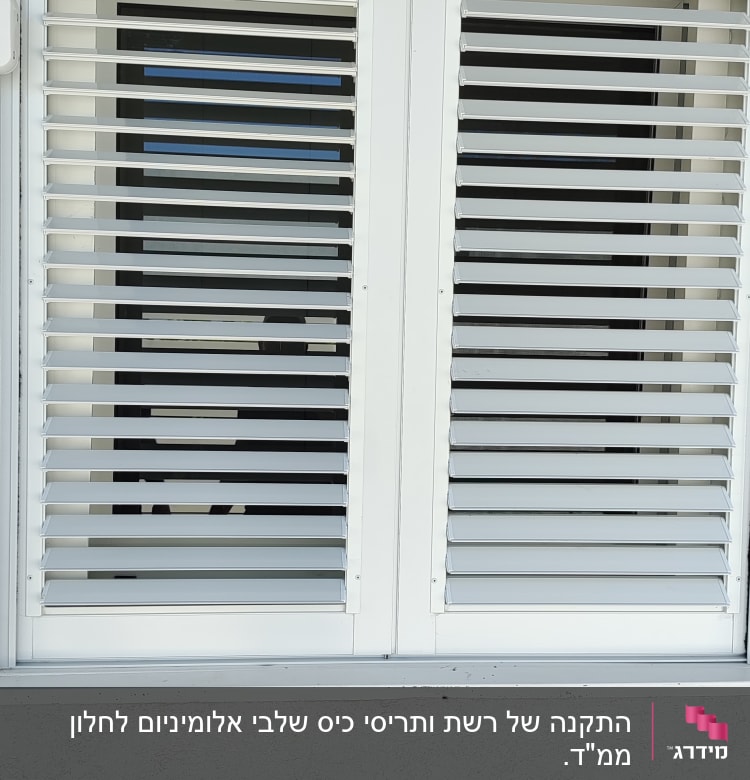 תריסי אלומיניום לבנים על חלון זכוכית.